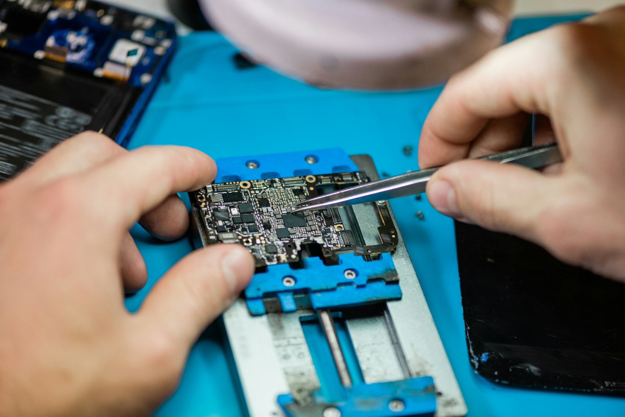 Tweezers in hands of professional repairman during work with tiny details